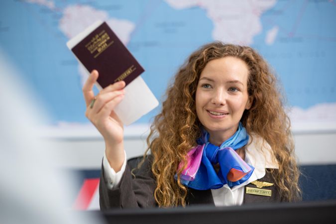 Woman working in airport holding traveler’s passport at check in
