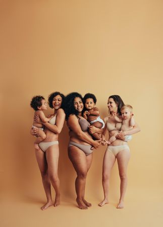Group of women wearing undergarments standing proud with their infants