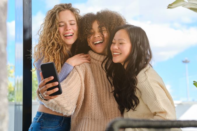 Joyful diverse friends taking self shot on smartphone
