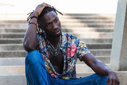 Stylish Black hipster man sitting on stairs in city