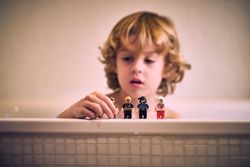 Cute kid playing with mini toys while taking bath