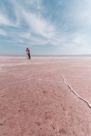 Happy relaxed travelers enjoying unusual scenery of pink salt lake in sunny day