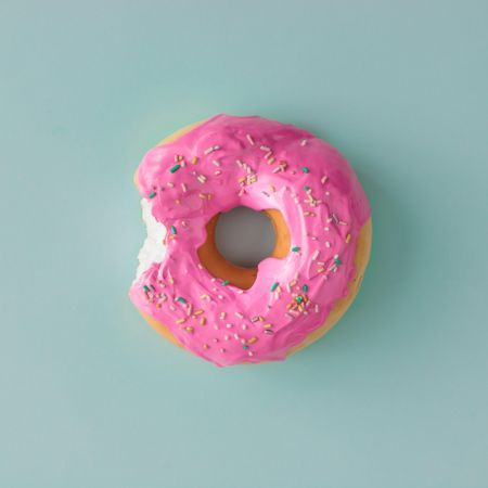 Pink glazed donut on blue pastel background