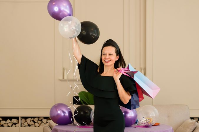 Woman in dress holding balloons and posing at party