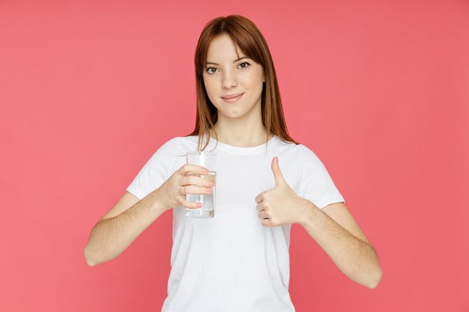 Concept of people, woman with glass of water on pink background
