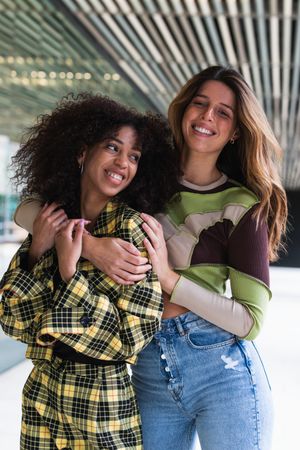 Content diverse female friends embracing in city