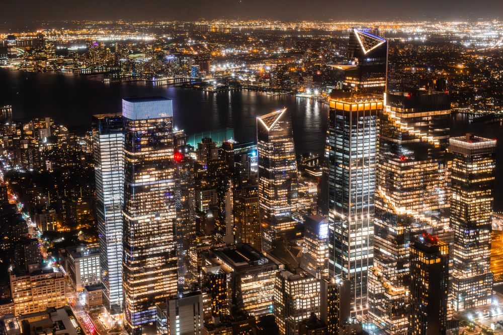 New York City Aerial Night Cityscape with Stunning Manhattan Landmarks, Skyscrapers and Residential Buildings. Wide Angle Panoramic Helicopter View of a Popular Travel Destination