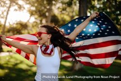 Young woman enjoying in park holding USA flag 56eej0