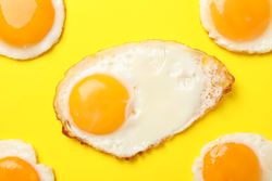 Rows of friend eggs sunny side up on yellow table