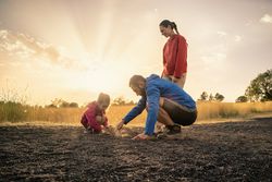 Father and daughter exploring the ground as a family in nature at sunset.
