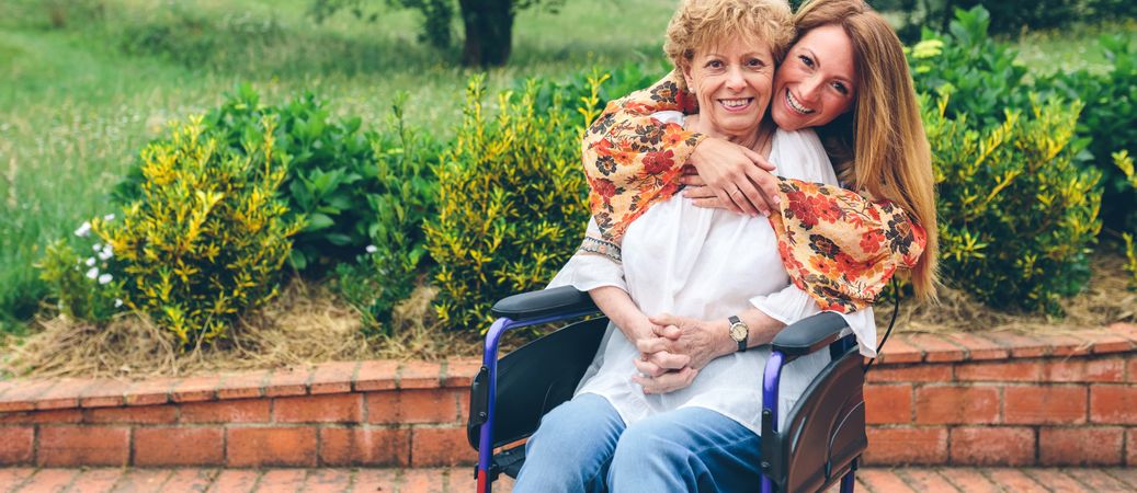 Daughter embracing her mother in wheelchair