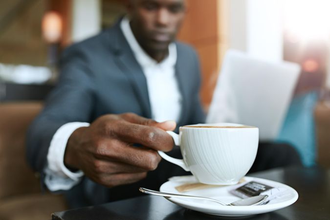 Close up shot of young man 's hand picking up cup of coffee