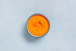 Pumpkin soup on baby blue background, top view