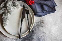 Top view of Christmas table setting with snowy pine branch and holly