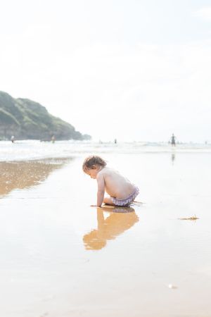 Toddler baby on wet sunny beach