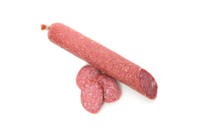 Salami stick and slices in plain room