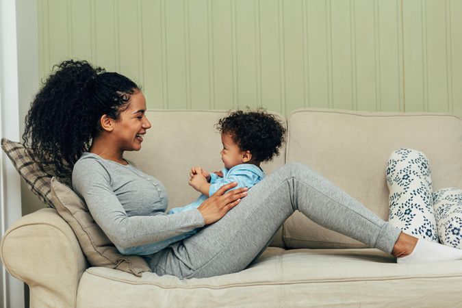 Mother smiling at cute toddler on the sofa