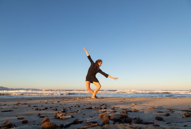 Young woman dancing and posing near water on shore