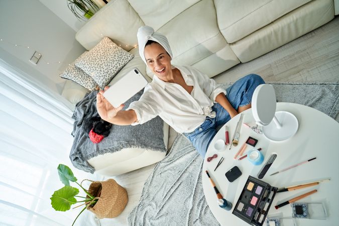 Cheerful woman blogger taking selfie on smartphone after applyin