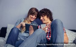 Couple in love looking electronic tablet and laughing relaxing in bed 4Bam8X