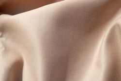 Close up silk shiny light brown fabric background texture.
