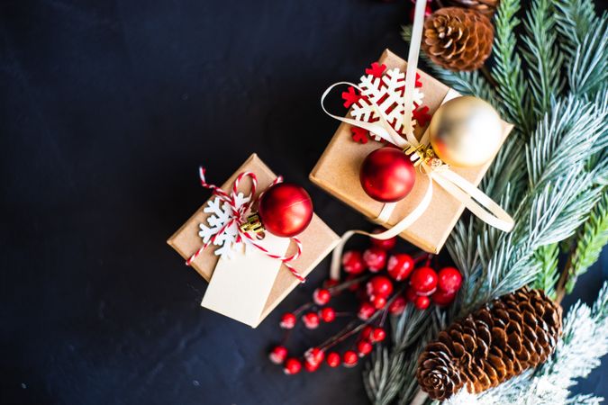 Two Christmas presents with baubles and surrounded by pine branch