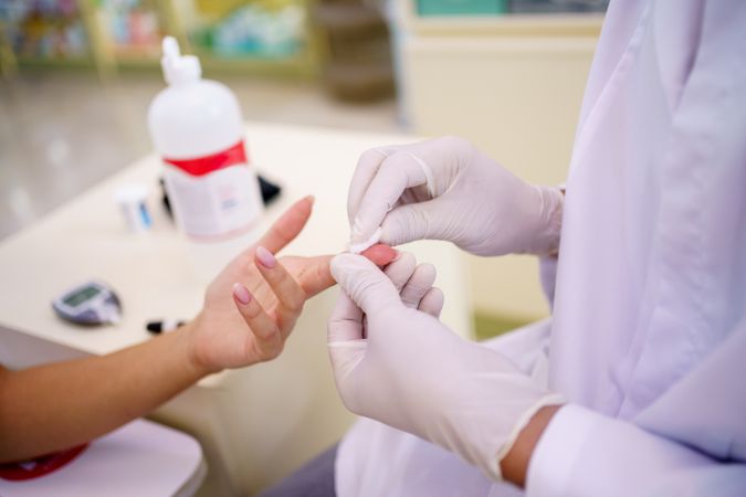 Woman having blood extracted from finger