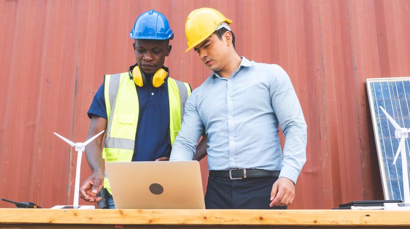 Two men on construction site brainstorming and working together