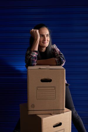 Positive woman leaning on carton boxes