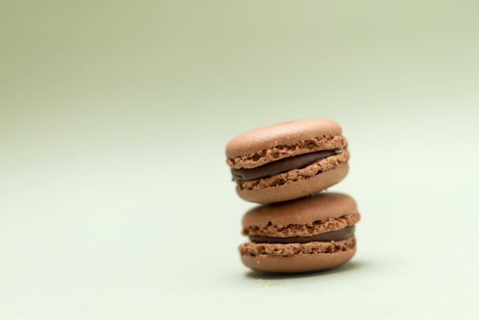 Two chocolate macaroons on a green table with copy space