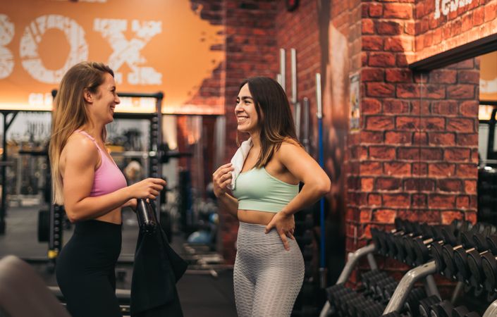 two young women talking in the gym while resting
