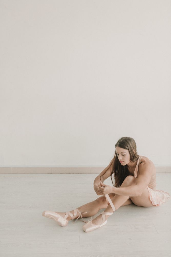 ballerina getting into ballet shoes in studio