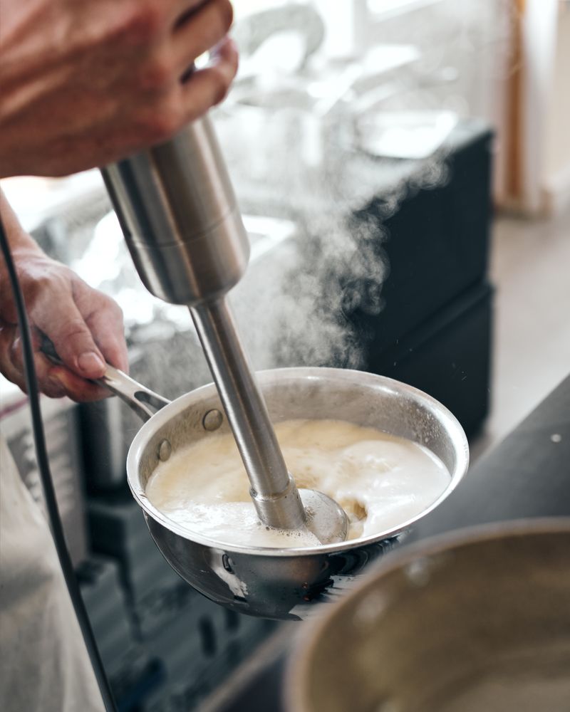 Chef mixing hot cream with a mixer