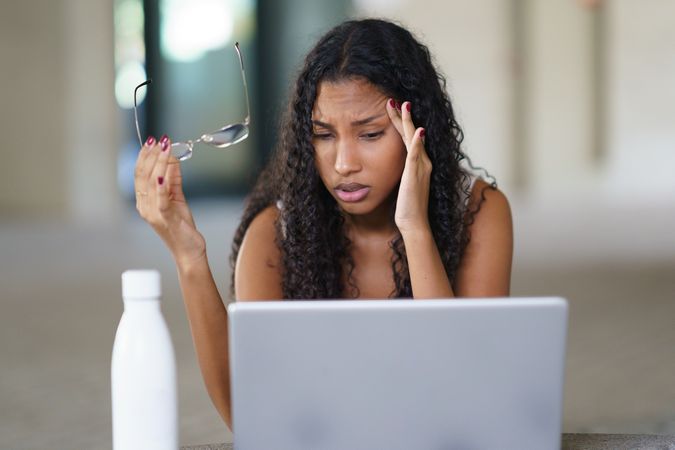A frustrated woman is working diligently on her laptop within a modern and stylish workspace