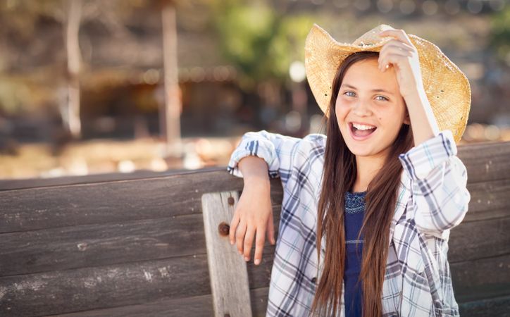 Girl Wearing Cowboy Hat Enjoying The Pumpkin Patch on a Sunny Fall Day.