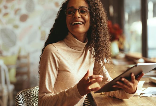 Smiling woman sitting at a cafe with her digital tablet