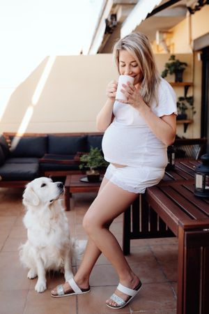 Pregnant woman having breakfast with dog