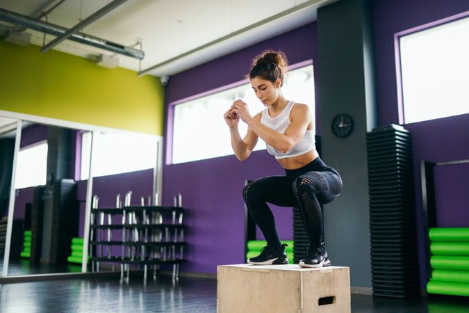 Woman standing exercising lower body with box jumps