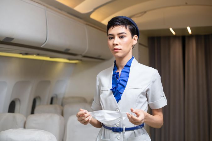Flight attendant getting ready to put on facemask in airplane