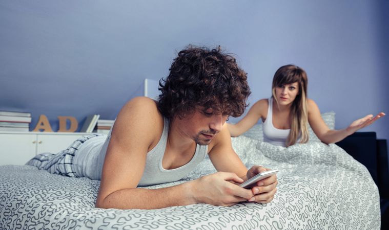Man using smartphone during quarrel with woman