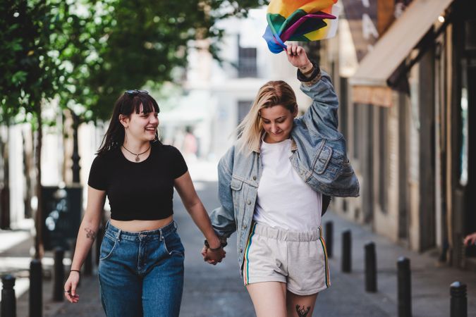 Lesbian couple with LGBT flag walking on street