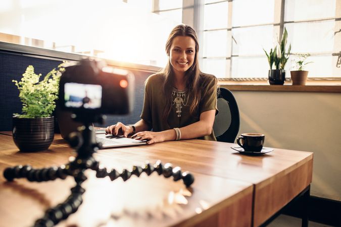 Happy woman smiling at camera while working on video content
