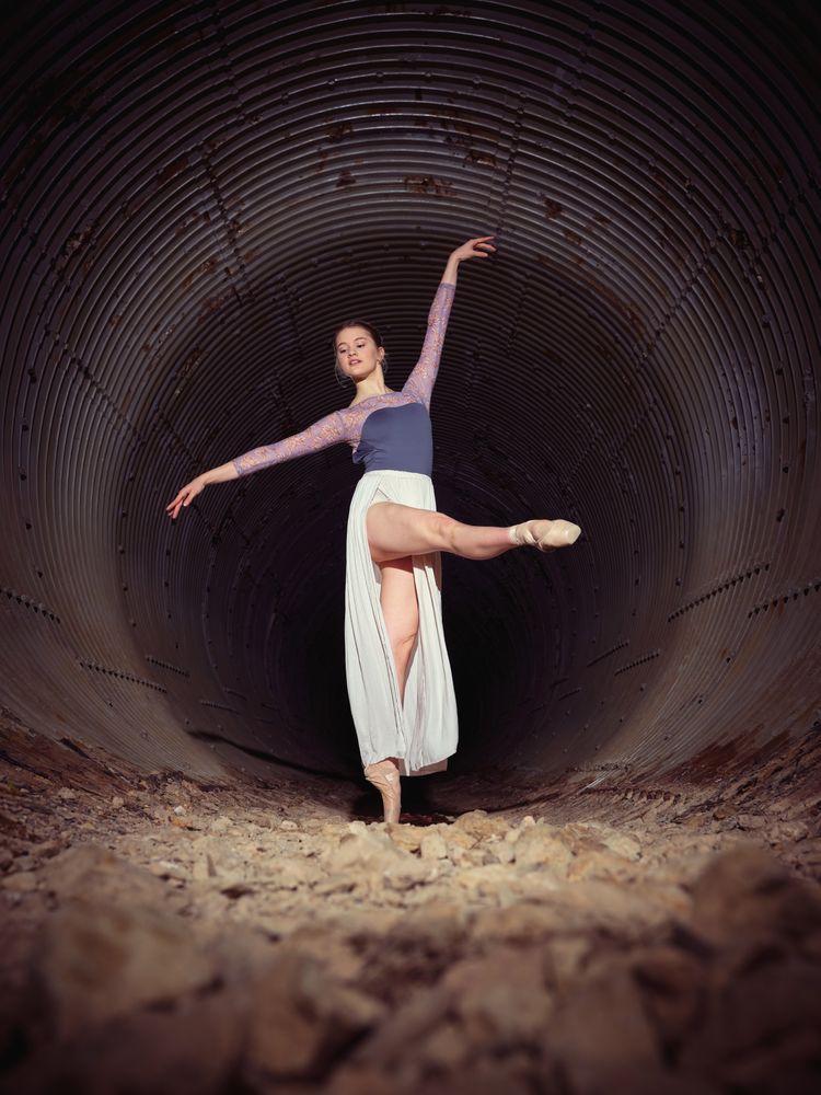 Flexible woman dancing ballet in old tunnel