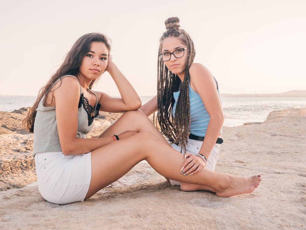 Smiling trendy young women relaxing on seashore