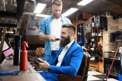 Man in sharp blue suit having his beard trimmed