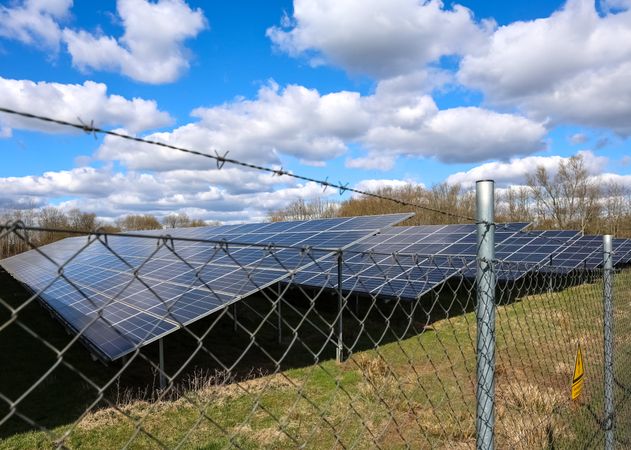 Photovoltaic power plant generating sustainable energy behind barbed wire fence