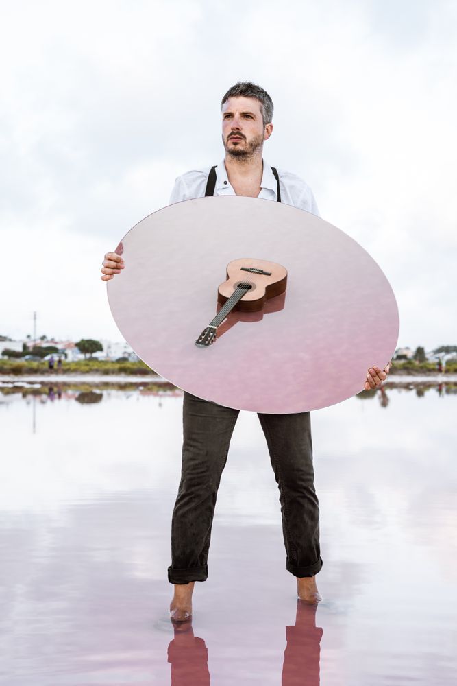 Man holding mirror with guitar reflection