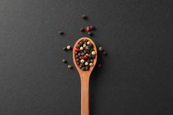 Looking down at wooden spoon of colorful peppercorns