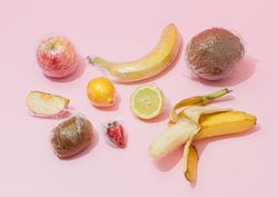 Plastic wrapped fruit on pink background