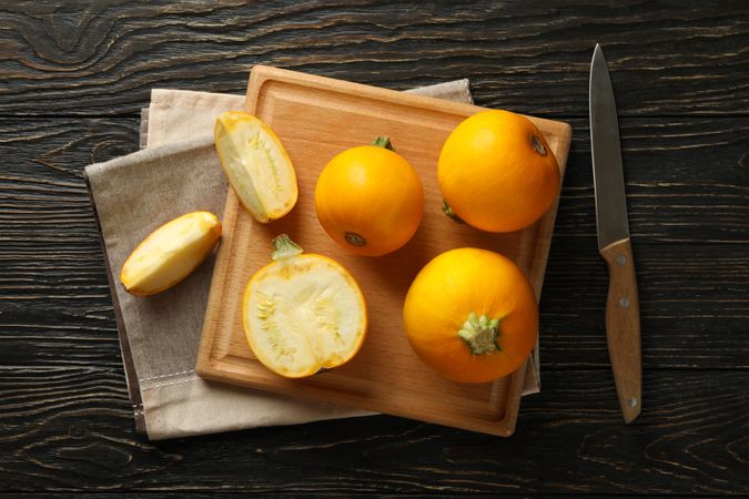 Board with zucchini, knife and towel on wooden background